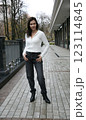 Street portrait of a 51 years old woman in fashionable graphite jeans and white fluffy hoodie and black high-heeled ankle boots 123114845