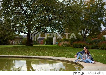 Autumn Serenity: Couple Relaxing by a Reflective Pond in an Ivy-Covered Garden with Vibrant Foliage Autumn Serenity: Couple Relaxing by a Reflective Pond in an Ivy-Covered Garden with Vibrant Foliage 123115012
