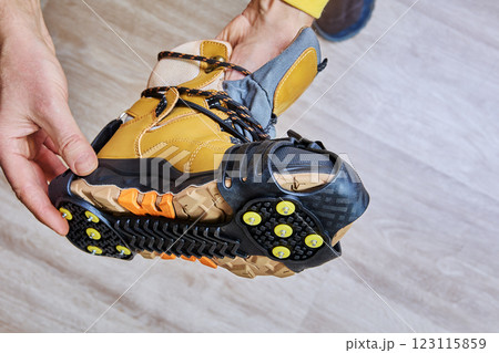 Anti-slip shoe covers with yellow spikes and durable rubber base are fitted to hiking boot for icy conditions. Anti-slip shoe covers with yellow spikes and durable rubber base are fitted to hiking boot for icy conditions. 123115859