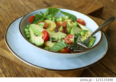Pasta salad with green peas, avocado, cherry tomatoes and basil on rustic wooden background. Top view. 123115890