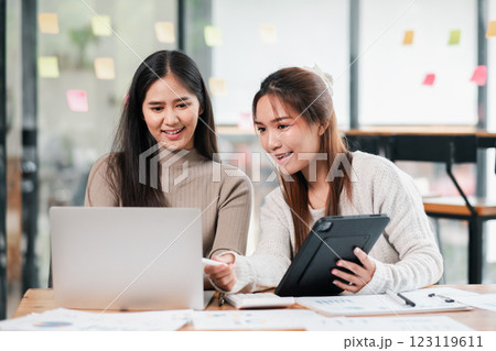 Two young women working together in a modern office, using a laptop and tablet for collaboration and brainstorming. Two young women working together in a modern office, using a laptop and tablet for collaboration and brainstorming. 123119611