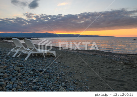 Sunset tranquility at a serene beach with lounge chairs overlooking the calm sea 123120513
