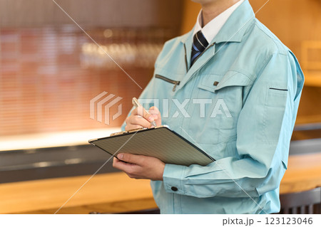 飲食店で点検をする作業着を着た男性	 123123046