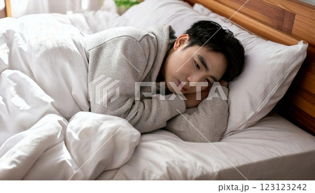 気怠そうにベッドで寝る若い男性 123123242