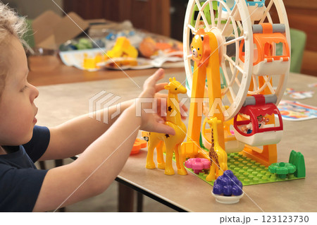 Child plays with a plastic constructor at home on table. Children and educational games. Animals of Africa and an amusement park. Child plays with a plastic constructor at home on table. Children and educational games. Animals of Africa and an amusement park. 123123730