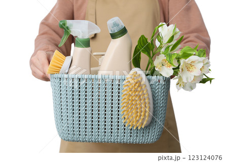 Spring cleaning, flowers, household chemicals and brushes in basket in woman`s hands, isolated on white background, PNG 123124076