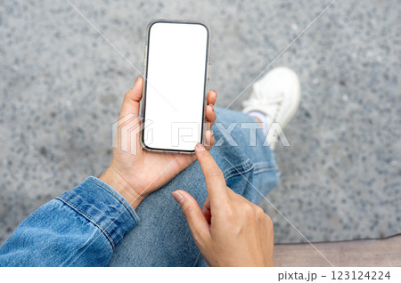 The hand in a denim jacket holding a smartphone and pointing at the screen. 123124224