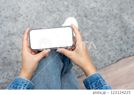the pair of hand in denim jacket and jean holding a smartphone. 123124225
