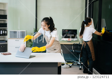 Two professional cleaners tidying a stylish space with a smile. Experience efficient and friendly house cleaning 123124711