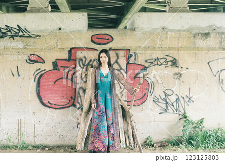 高架下の落書きの前でポーズをとる女性 123125803