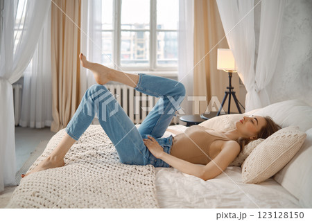 Relaxing woman enjoying leisure time on a bed in a cozy bedroom during daylight hours 123128150