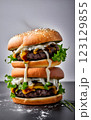 An impressive double-decker burger stacked with fresh lettuce, onions, cheese, and dripping sauce, with ingredients flying dramatically in the background, creating an exciting food explosion. 123129855