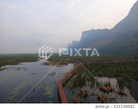 Wooden bridge and pavilion in wetland with the limestone mountain in mist , Path on the lagoon with reflection in water , Khao Sam Roi Yot National Park , Thailand Wooden bridge and pavilion in wetland with the limestone mountain in mist , Path on the lagoon with reflection in water , Khao Sam Roi Yot National Park , Thailand 123130082