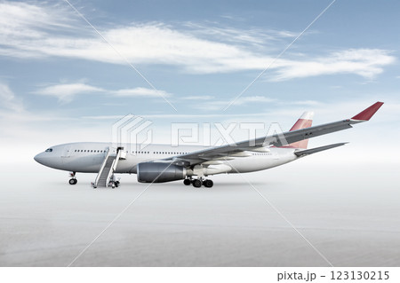 Wide body passenger airplane with boarding stairs on bright background with sky 123130215