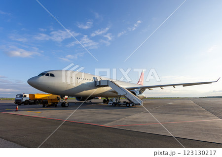 Wide body passenger jetliner with aircraft steps at the airport. Airfield tanker refueling an airplane 123130217