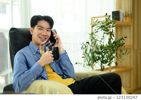Smiling man enjoying a coffee and talking on the phone in a cozy home 123130247