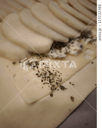 Gourmet pastry layering delicate cheese, ripe pear slices, and fresh herbs, revealing intricate culinary craftsmanship easy dinner for Valentines day 123132368