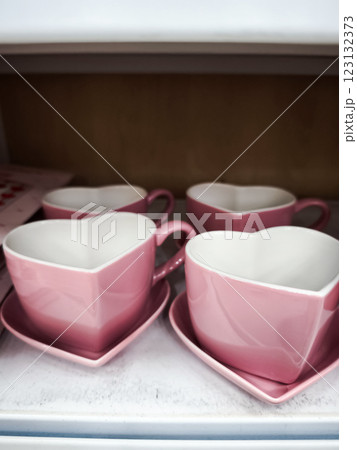 Pink heart shaped teacups and saucers are neatly arranged on a shelf, ready for a romantic occasion or everyday use Valentines Day 123132373