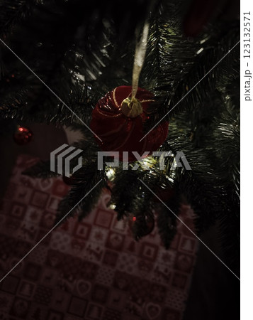 Red christmas ball hanging on christmas tree with gift bag below Red christmas ball hanging on christmas tree with gift bag below 123132571