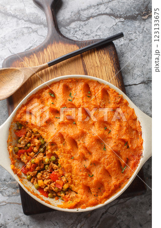 Homemade Sweet Potato Shepherd's Pie with mince and seasonal vegetables close-up in baking dish on wooden board. Vertical top view Homemade Sweet Potato Shepherd's Pie with mince and seasonal vegetables close-up in baking dish on wooden board. Vertical top view 123133675