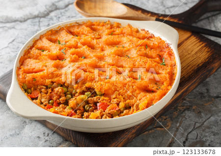 Sweet potato shepherd's pie with ground turkey, green peas, onions, peppers and tomatoes close-up in a baking dish. Horizontal 123133678