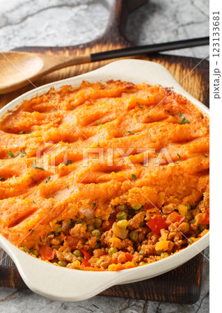 Healthy shepherd's pie made with ground meat, vegetables and topped with a layer of fluffy mashed sweet potatoes closeup on the baking dish. Vertical 123133681