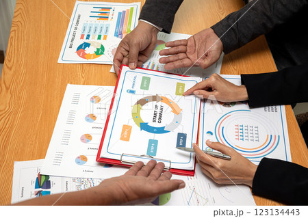 Business professionals discussing a startup strategy plan with charts and graphs on wooden table, analyzing company growth, investment opportunities, and financial planning 123134443
