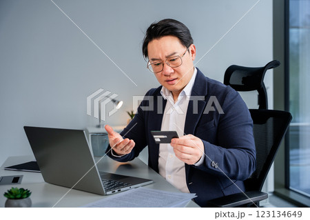 Professional Businessman Analyzing a Credit Card At Work in Modern Office 123134649