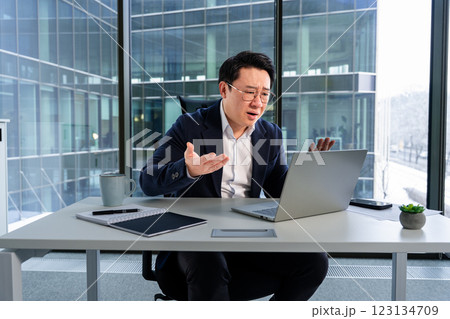Frustrated Business Professional Working at a Laptop in a Modern Office Setting 123134709