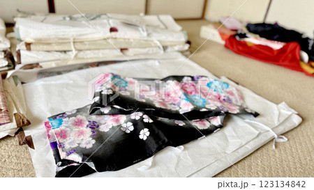 たとう紙の上に置かれた黒地に花模様の浴衣と複数の着物 たとう紙の上に置かれた黒地に花模様の浴衣と複数の着物 123134842