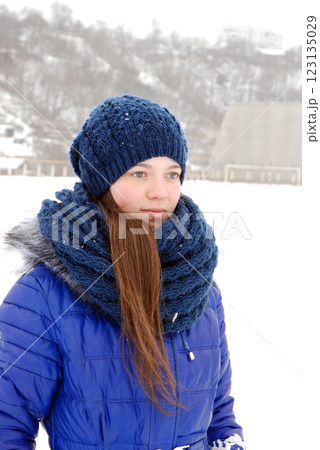 Winter portrait of a woman in blue jacket and knitted accessories in snowy landscape 123135029