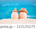 Happy easter. White eggs with hats on sandy beach of sea or ocean. Holiday postcard in hot country. Travel, spring, summer, vacations. Copy space 123135275