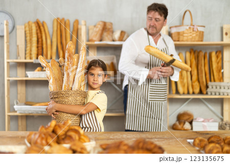 Girl daddy assistant poses in bakery with baguettes of bread Girl daddy assistant poses in bakery with baguettes of bread 123135675