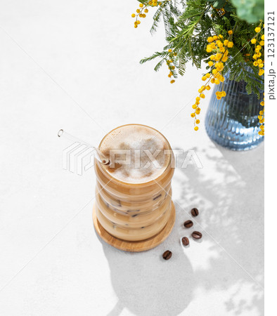 Cold coffee latte or mocha in a glass with milk and ice on a light background with a bouquet Cold coffee latte or mocha in a glass with milk and ice on a light background with a bouquet 123137121