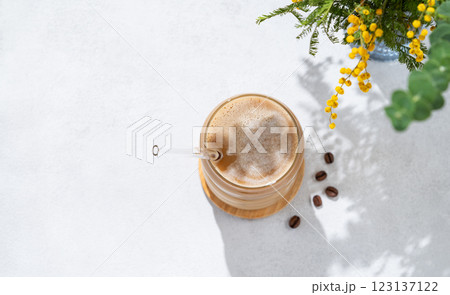 Cold coffee latte or mocha in a glass with milk and ice on a light background with a bouquet  123137122
