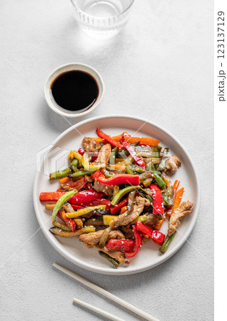 Stir-fry with vegetables and meat on wooden board on white background Stir-fry with vegetables and meat on wooden board on white background 123137129