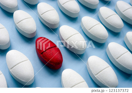 Rows of white pills and one red pill as a symbol of medical choice and uniqueness. 123137372