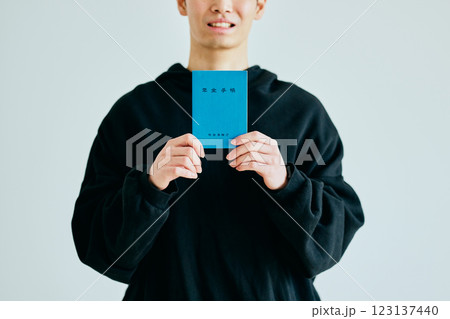 年金手帳を持つ20代の若い男性 年金手帳を持つ20代の若い男性 123137440