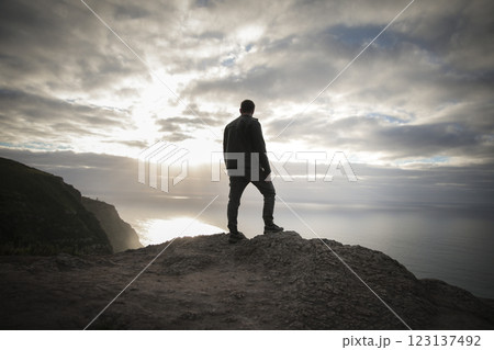 Hiker contemplating dramatic sunset over the ocean from a cliff in madeira 123137492