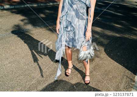 Woman in stylish gray dress holding chic purse outdoors Woman in stylish gray dress holding chic purse outdoors 123137871