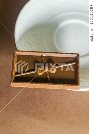 Elegant chocolate bar with bow design placed on a decorative plate, close-up. High quality photo 123139297