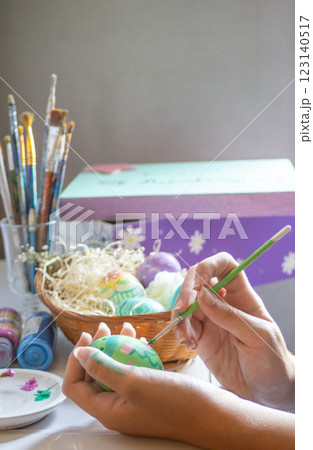 Girl painting Easter eggs while the sun is coming through the window. Girl painting Easter eggs while the sun is coming through the window. 123140517