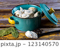 Raw dumplings in a blue bowl on a wooden background. 123140570