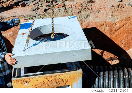Construction worker carefully places concrete slab over manhole opening at job site in build works area 123142105