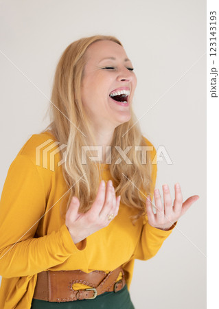 Portrait of confident beautiful woman laughing, with long blende hair, wearing casual clothes, standing in welcoming pose with open hands, meditating. Portrait of confident beautiful woman laughing, with long blende hair, wearing casual clothes, standing in welcoming pose with open hands, meditating. 123143193