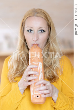 Portrait of female musician playing on traditional clay flute. Woman playing ocarina 123143195