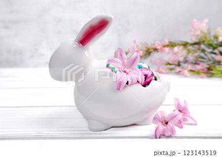 Easter bunny and jar with chocolate eggs, pink flowers. Easter bunny and jar with chocolate eggs, pink flowers. 123143519