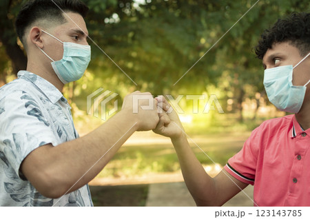 Two young men clashing their fists, image of two young men bumping their fists in a friendly way, close up of two fists bumping in a friendly way 123143785
