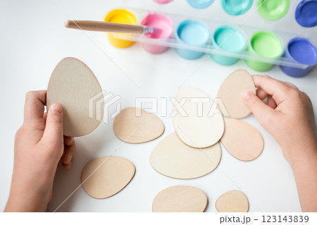 Child creating wooden Easter eggs with colorful paints for art project 123143839