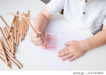 Child drawing with colored pencils on white paper 123143845